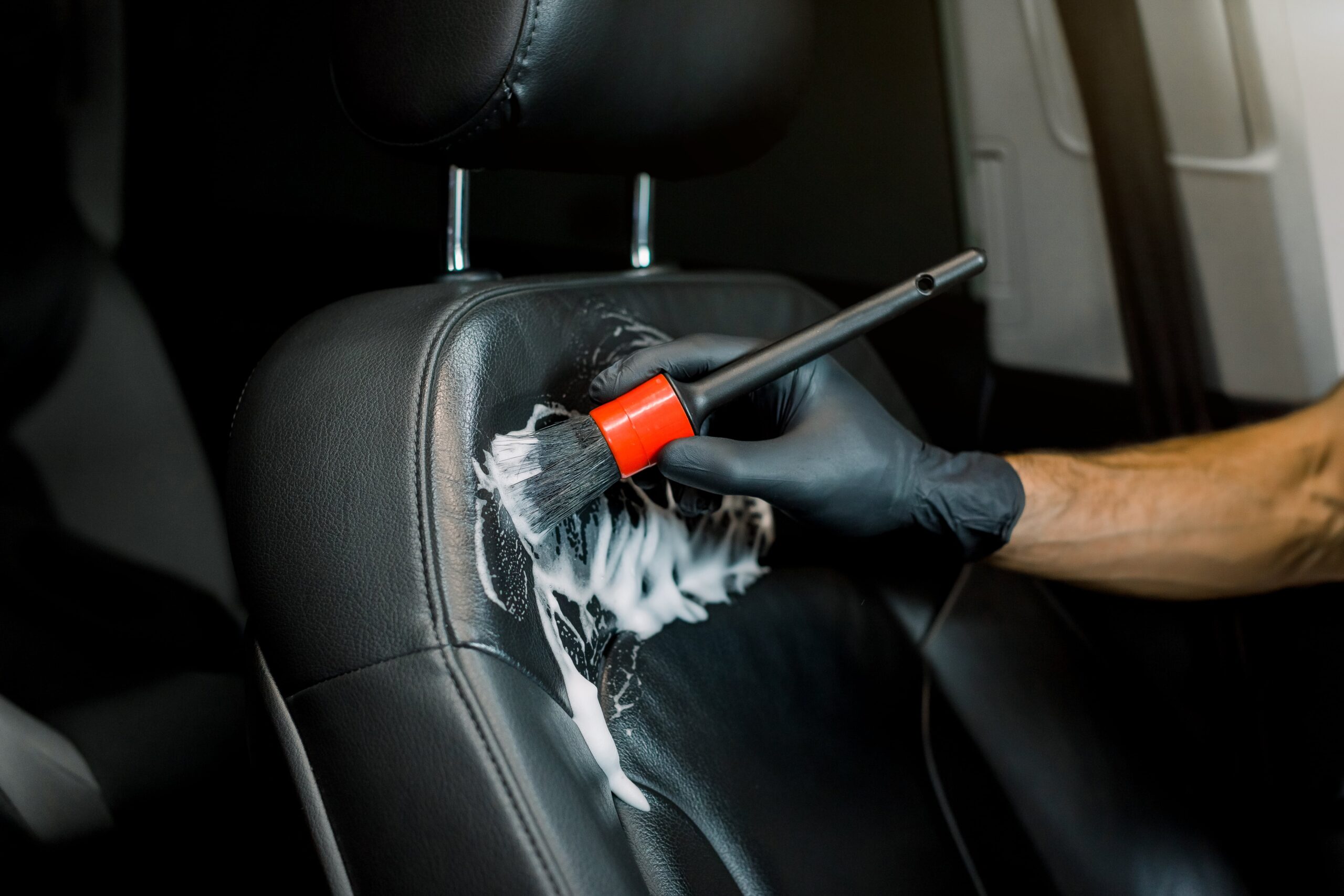 Hand washing car interior and seat by a soft brush with foam.
